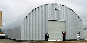 Stalowe hale łukowe (typy hal łukowych) - hala łukowa C o pionowych ściana i łukowym dachu zastosowana jako magazyn przemysłowy.